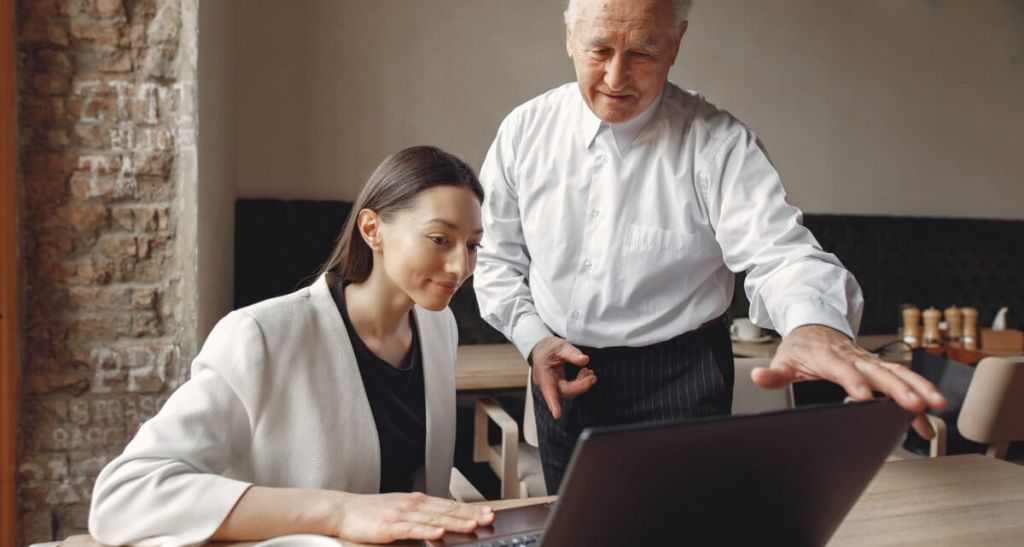 Two business partners working with a laptop in a cafe