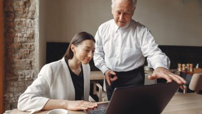 Two business partners working with a laptop in a cafe